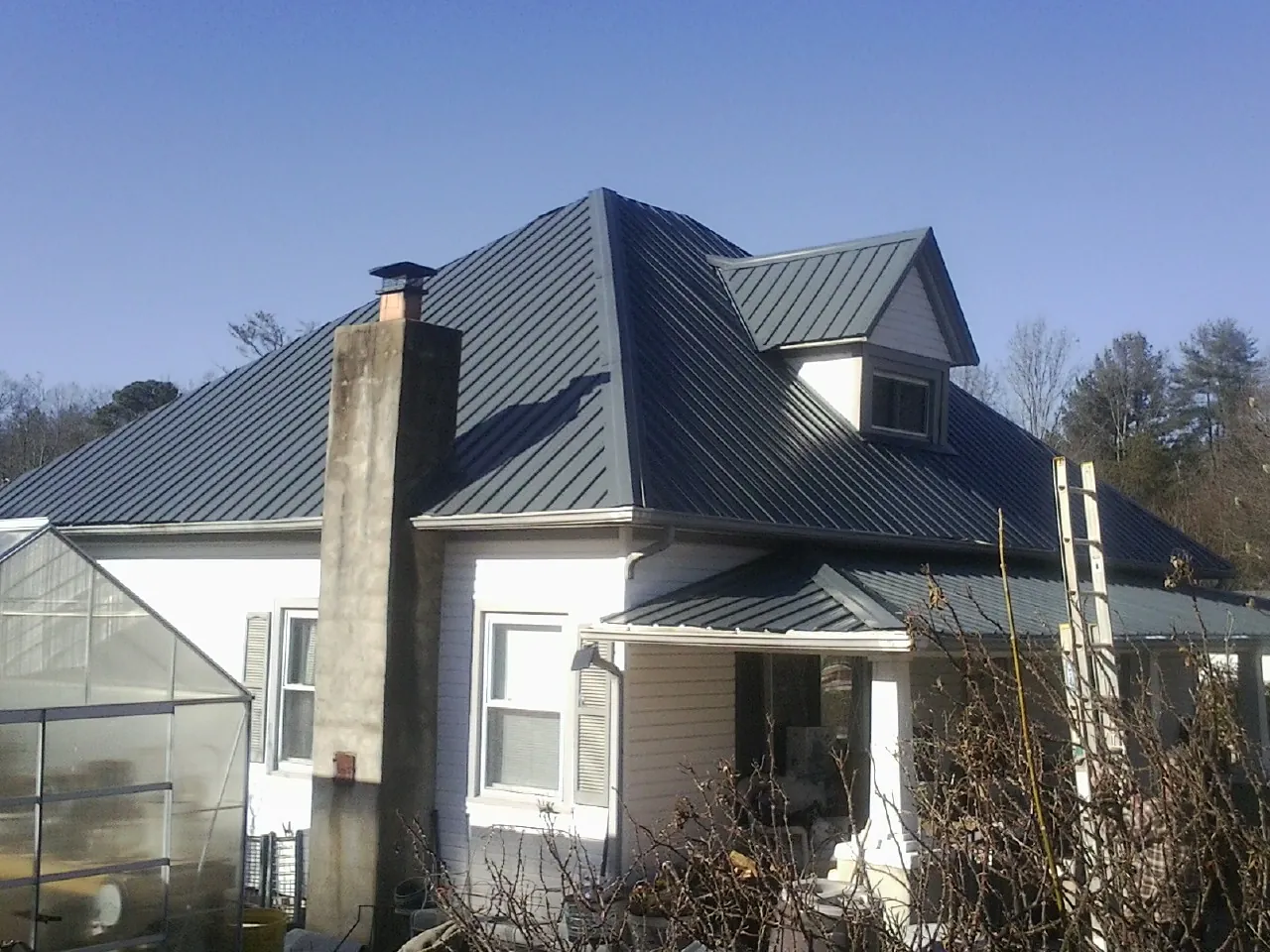 Dark blue standing seam metal roof on a white farmhouse with dormer — Slate & Tile Roof Repair by Roofing Brothers in Rockhill Furnace