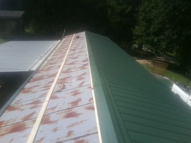 Old rusted panels beside newly installed green metal roofing — Wind Damage Roof Repair by Roofing Brothers in Rockhill Furnace
