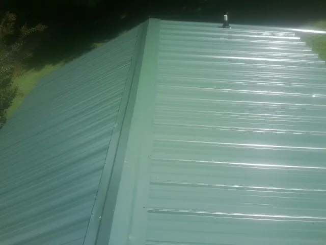 New green metal panels meeting at the ridge of a roof — Flat Roof Repair work by our crew in Rockhill Furnace