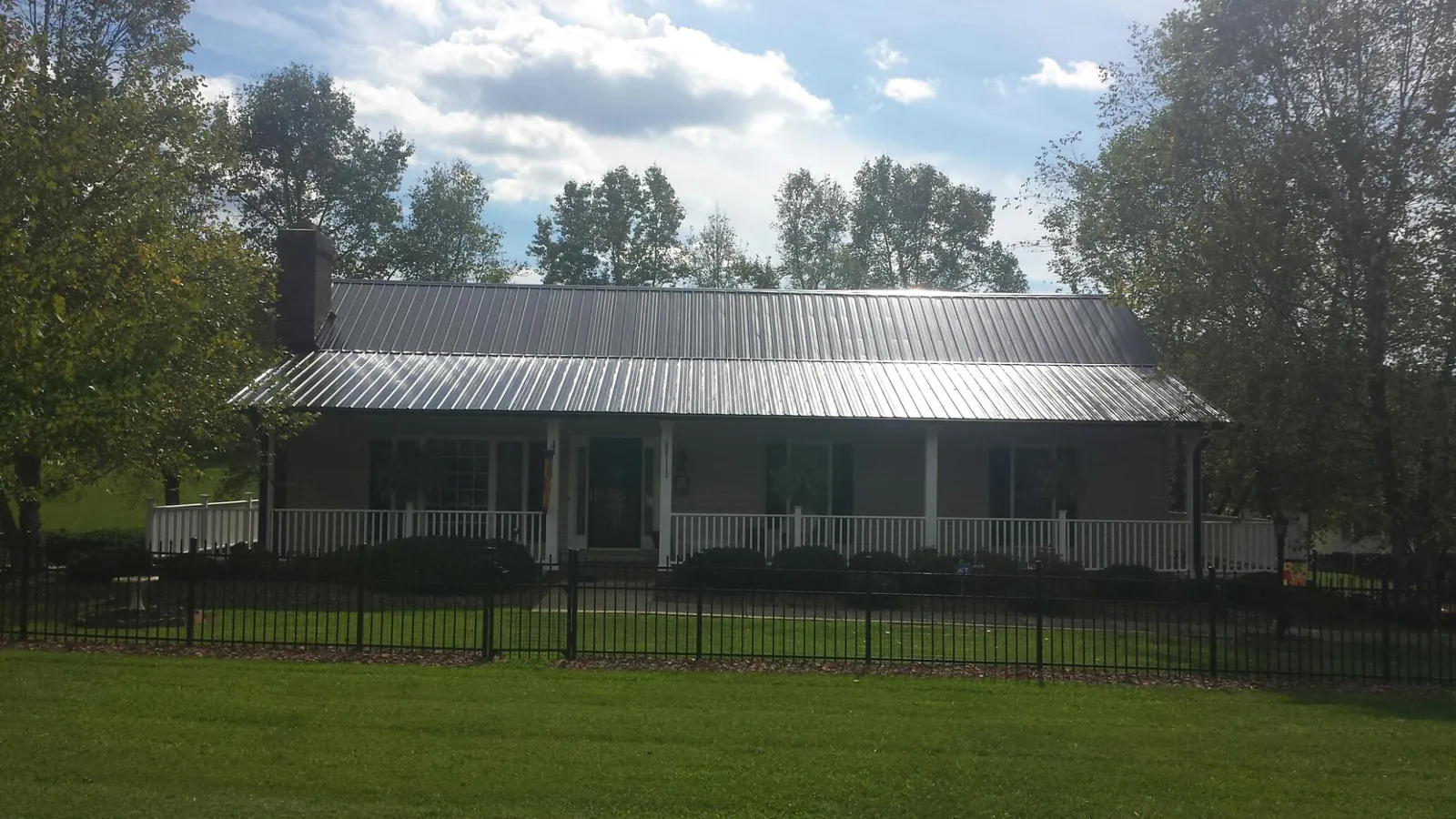 Gray metal roof on a brick ranch with a full width front porch — Gutter Guard Installation work by our crew in Rockhill Furnace