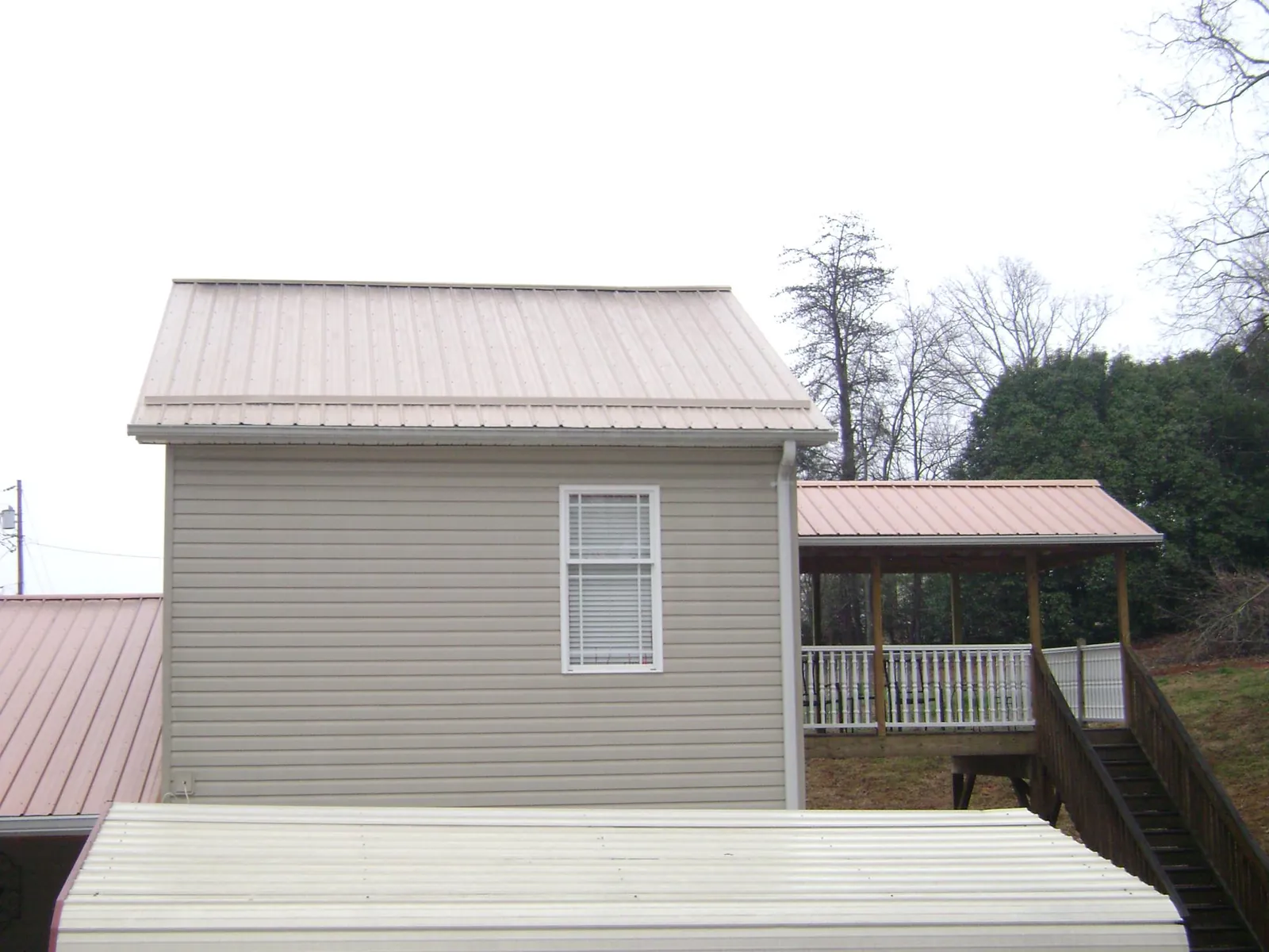 Tan metal roofs on a two story addition and attached porch, from a Roof Replacement job in Rockhill Furnace