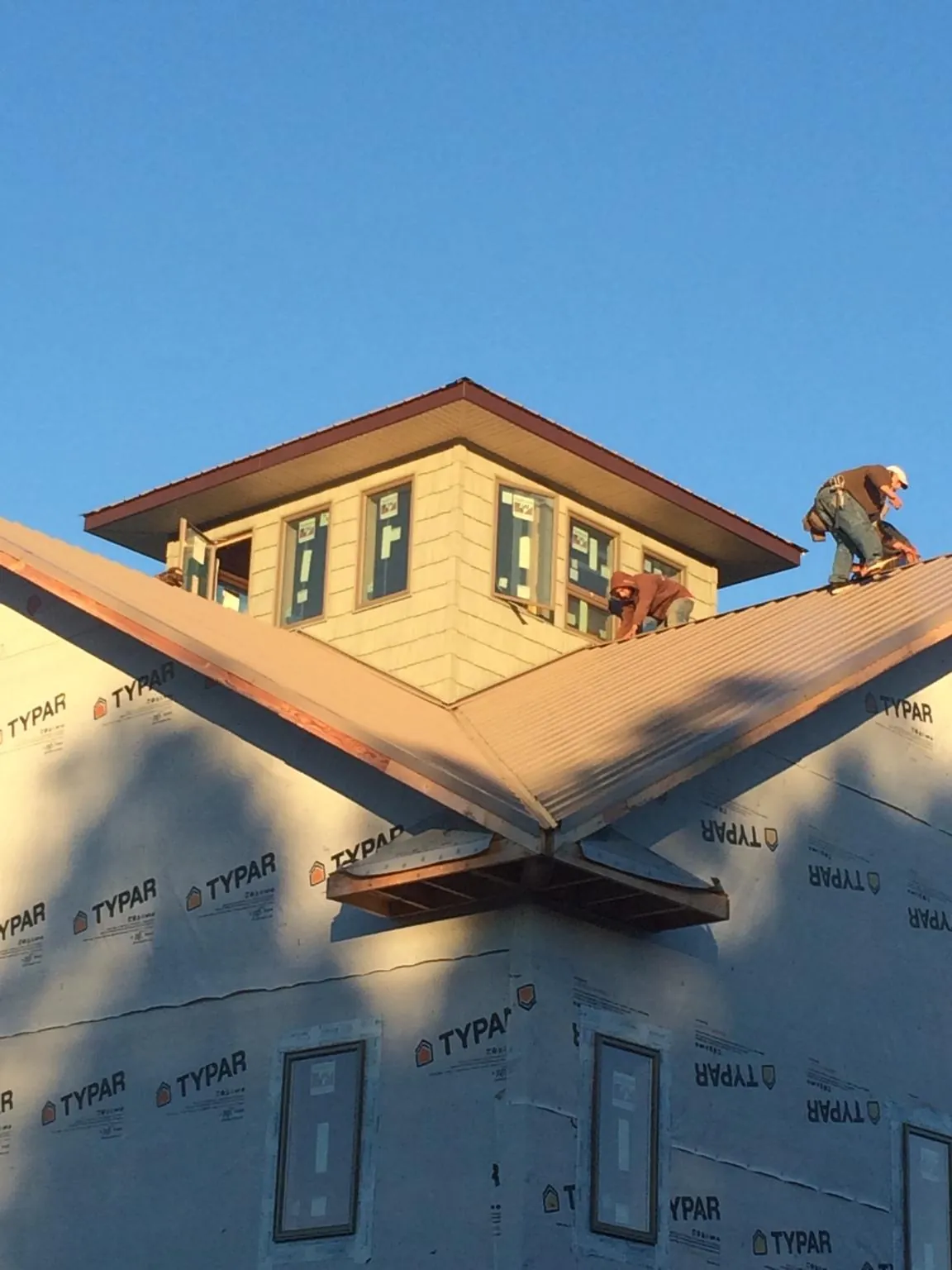 Roofers working around a rooftop cupola on a new metal roof at sunset — Roof Waterproofing in Rockhill Furnace by Roofing Brothers